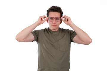 Man wearing a green shirt on a white background putting on glasses