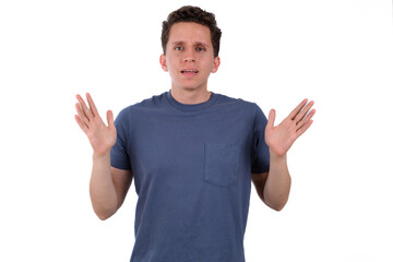 Man wearing a blue shirt on a white background making a sign of repulsion, of rejection, of dislike