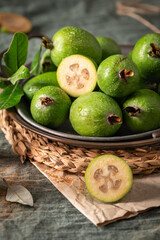 A rustic still life with ripe pineapple guavas, some cut open to reveal the fleshy pulp, on a small plate and in a basket