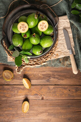 Overhead shot of a rustic still life with ripe pineapple guavas, some cut open to reveal the fleshy pulp, on a small plate and in a basket