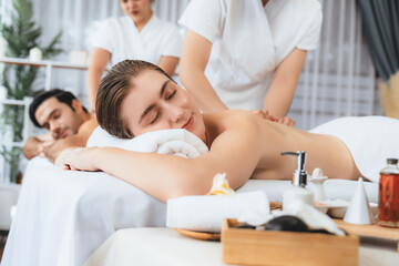 Obraz premium Caucasian couple customer enjoying relaxing anti-stress spa massage and pampering with beauty skin recreation leisure in day light ambient salon spa at luxury resort or hotel. Quiescent