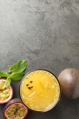 Tasty passion fruit drink with mint and fresh fruits on grey table, flat lay. Space for text