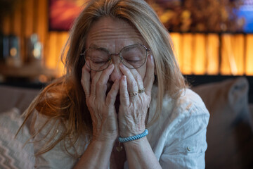 Portrait of a old tired woman with hands up her face