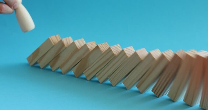 Risk. Woman pushing wooden blocks with figure on light blue background, closeup