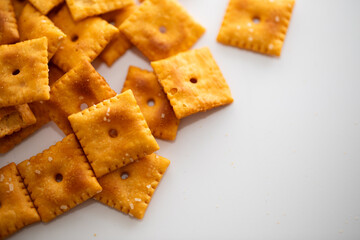 Salted Cheddar Cheese square crackers in the corner on white background