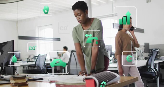 Design engineer scanning blueprints and tapping section while eco icons guiding design optimization