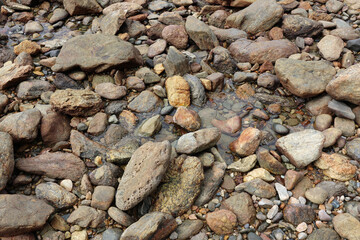 Rocks and stones with puddles of water at a beach abstract textured background