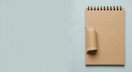 A spiral notebook with brown kraft paper and a torn, curled page. Top view flat lay on a plain background with copy space for text
