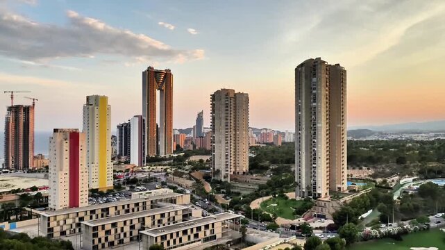An aerial view showcases a stunning skyline of towering skyscrapers amid urban hustle. A manicured golf course contrasts this lively scene, capturing modern city livings grandeur and tranquility