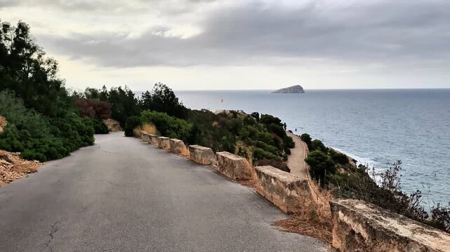 A winding road that leads directly to the vast ocean on a rather cloudy and slightly overcast day, creating a moody atmosphere