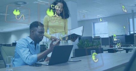 Male colleague opening laptop summoning energy icons while female noting chart for energy analysis - Powered by Adobe