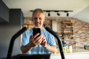 Senior man using smartphone while exercising