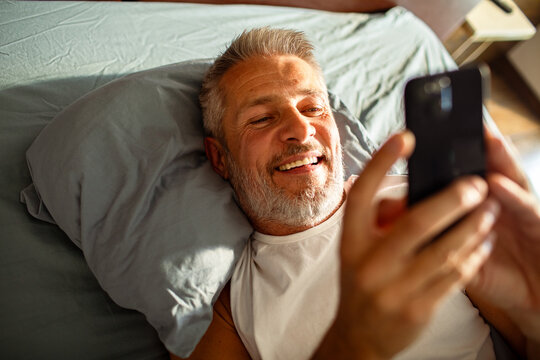Man using smartphone in bed