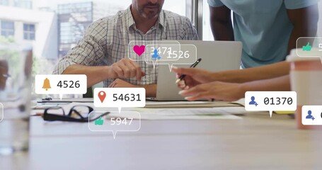 Man pointing at papers starting animated social media icons in marketing while team noting data - Powered by Adobe