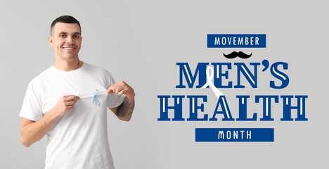 Young man with blue ribbon on grey background. November - men's health month