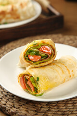 Ham and Vegetable Breakfast Wrap with Lettuce and Tomatoes on White Plate