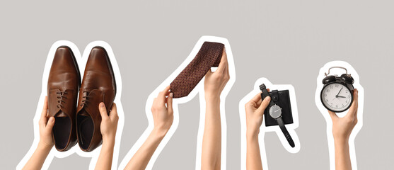 Hands holding men's accessories and alarm clock on grey background