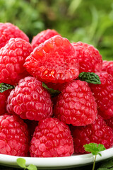 Fresh Red Raspberries with Green Leaves on White Plate - Healthy Organic Berry Fruit Close-up