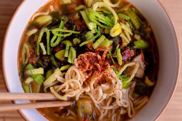 Bowl of Asian-style noodles with rich spices and umami seasoning. The dish features a vibrant and flavorful presentation, highlighting Asian cuisine and comfort food. Perfect for food photography, cul
