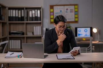 Fototapeta premium A man in a suit is sitting at a desk with a laptop and a tablet
