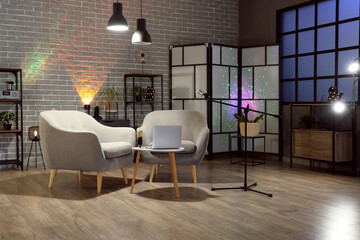 Interior of dark studio with podcaster's workplace, shelf units and glowing lamps