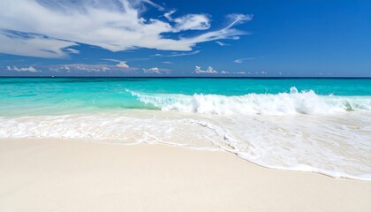 Fototapeta premium Turquoise ocean wave rolling onto white sand beach under a blue cloudy sky Tropical paradise.