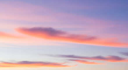 Fototapeta premium Soft pastel sunset sky with pink and orange clouds blending into a light blue gradient.