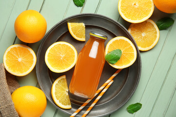 Bottle of fresh orange juice with mint and fruits on green wooden background