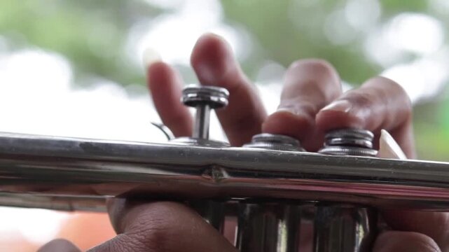 Close-up footage of hands performing on a trumpet, perfect for music, culture, and art concepts.