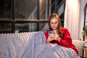 Asian woman relaxing home browsing social media on phone