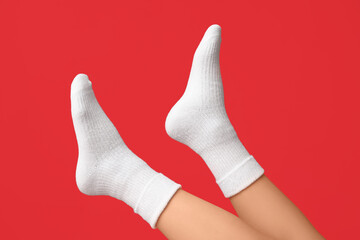 Legs of young woman in white cotton socks on red background