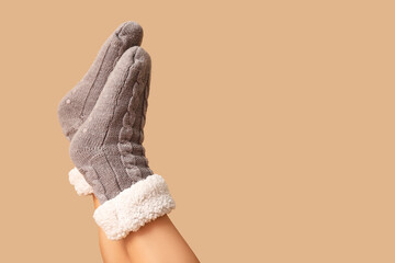 Legs of young woman in warm grey socks on brown background