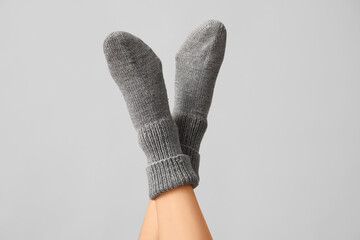Legs of young woman in warm knitted socks on grey background