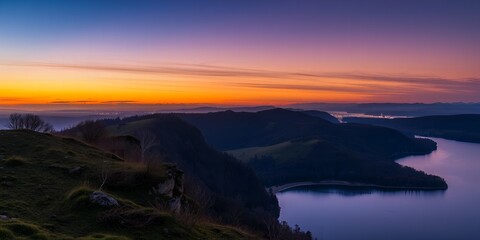 Breathtaking mountain landscape at sunset with a calm lake and distant city lights visible