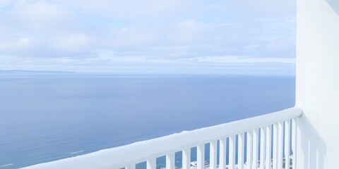 Expansive ocean view from a white balcony overlooking a distant shoreline under a cloudy sky