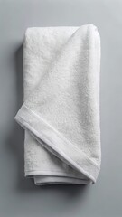 Folded clean white bathroom towel on gray background with copy space