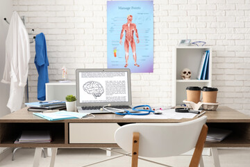 Medical student's workplace with laptop and coffee cups in clinic