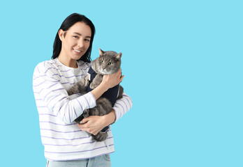 Obraz premium Young woman with cat in recovery suit after sterilization on blue background