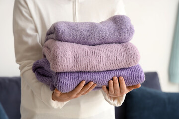 Woman with folded winter sweaters at home, closeup