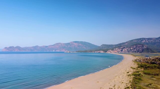 aerial footage capturing the stunning natural beauty of ztuzu Beach in Dalyan, Turkey. This pristine sandy spit, famously known as Turtle Beach, acts as a vital natural barrier between the freshwa