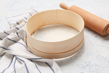 Wooden sieve for flour, rolling pin and napkin on wooden background