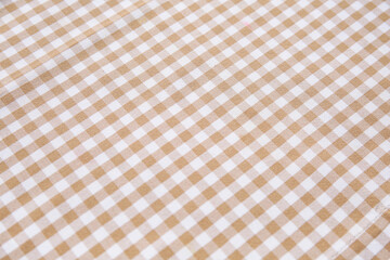 Beige checkered tablecloth as background, closeup