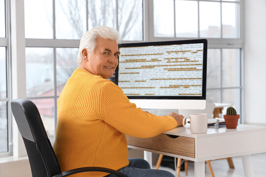 Senior programmer working at table in office