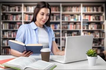 Student typing on laptop, studying in library