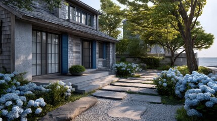 Obraz premium Elegant two-story coastal house with weathered wood siding, stone walls, blue shutters, manicured garden,