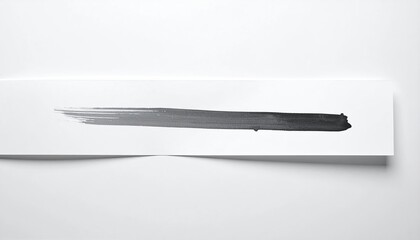 A gray brush stroke across a white paper strip, cast shadow below