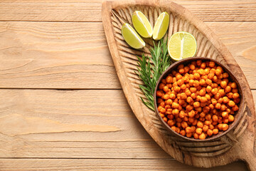 Bowl with tasty fried chickpeas, rosemary and lime on wooden background