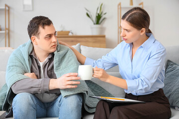Obraz premium Frozen male drug addict taking cup of tea from psychologist in office
