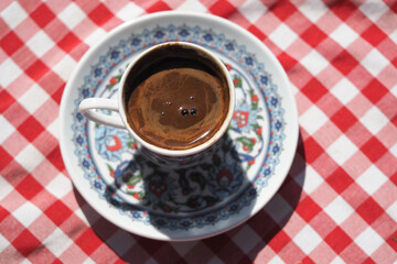 Turkish coffee on a decorative cup with checkered cloth