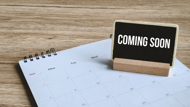 Coming Soon or Future Announcement Concept: Chalkboard Sign on a Desk Calendar Emphasizing New Product or Event on a Wood Table.